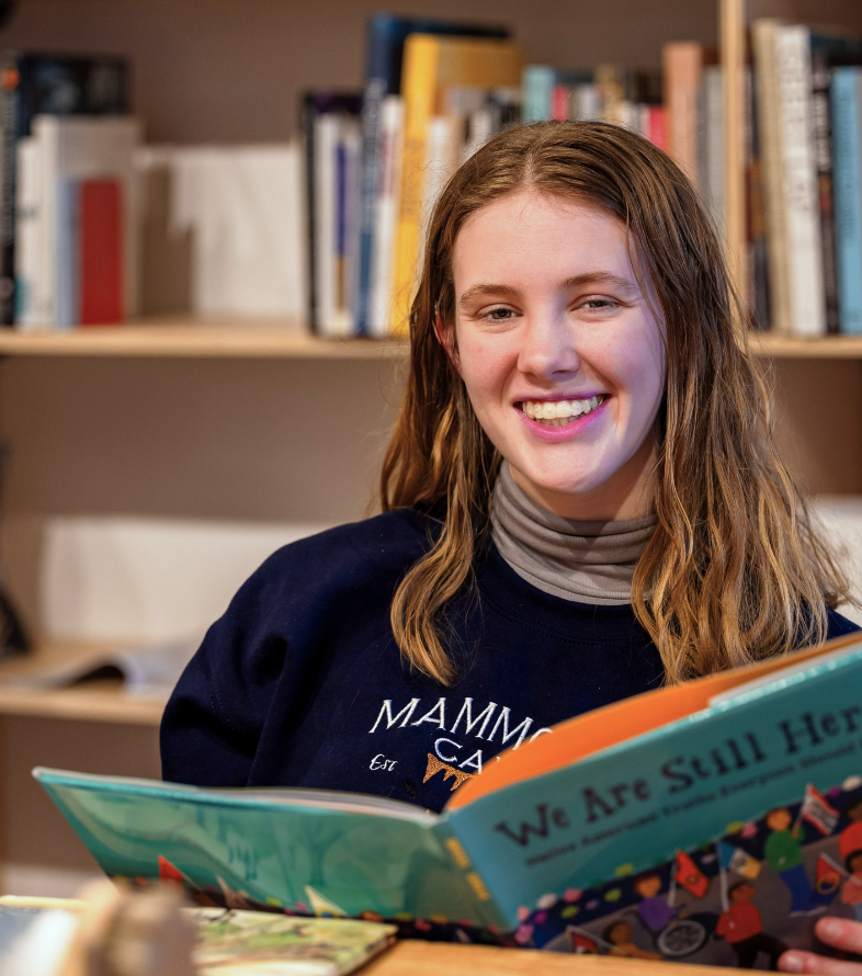 Female student reading a book in the grasselli library