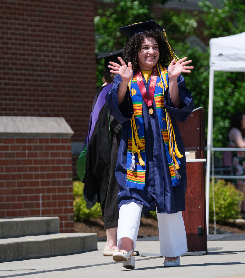 female student walking across commencement stage