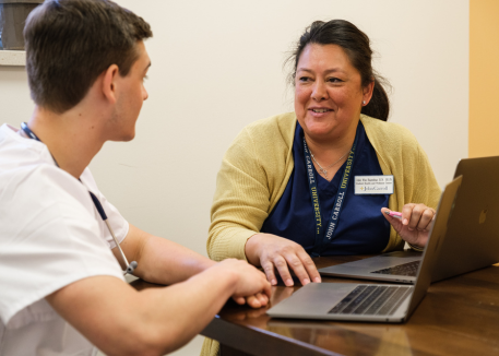 student and faculty discussing over laptop