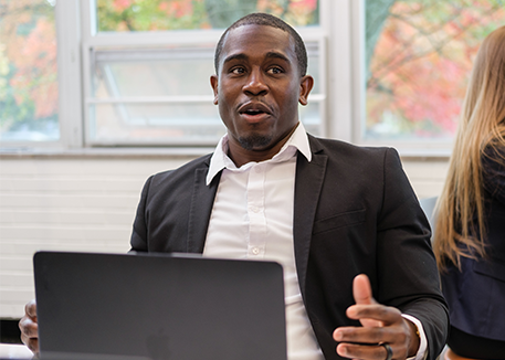 Picture of graduate student working on laptop with online program