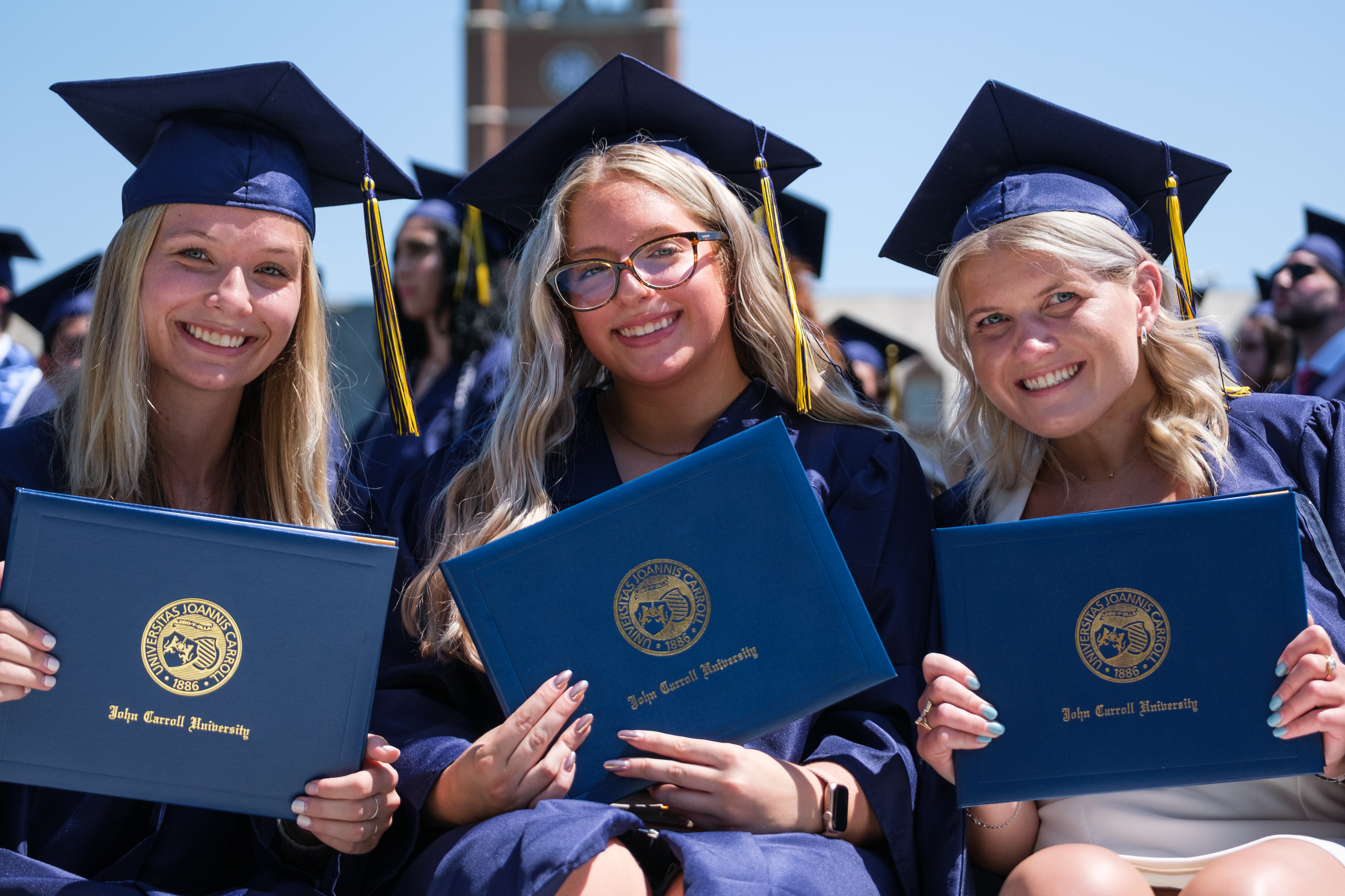 female students holding diplomas at commencement