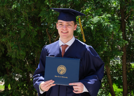 male student at commencement holding diploma