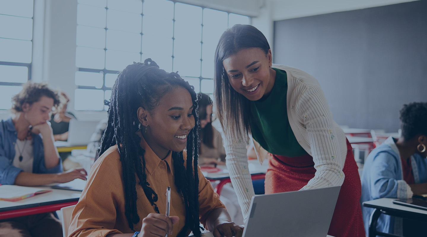 Picture of female teacher helping female high school student on her computer