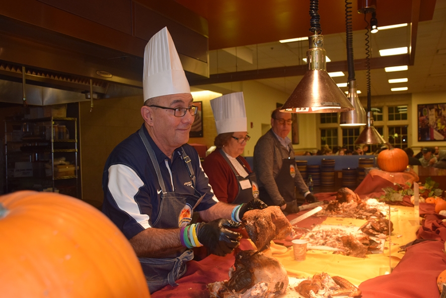 Faculty serve turkey to students in the dining hall. 