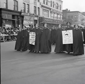 black and white photo of a group of nuns in long habits and bonnets marching in a Civil Rights protest holding signs reading SNCC - One Man One Vote and We March for Freedom and Equality for All Men