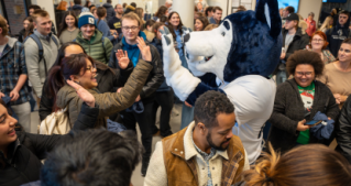 Lobo the Wolf high-fiving a student in the crowd at his release event.