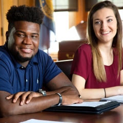 two students sitting at a desk smiling