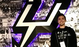 Brenan Betro stands in front of the San Antonio Spurs logo.