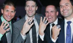 Four John Carroll alumni smile and show their Super Bowl rings. 