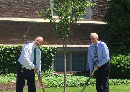 Jeff Your stand at left and Dr. Johnson stands at right, holding shovels near the oak tree.