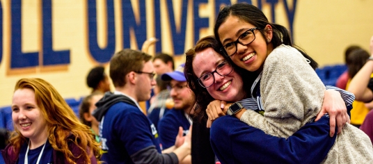 Picture of two current students hugging while volunteering for a campus event with incoming students